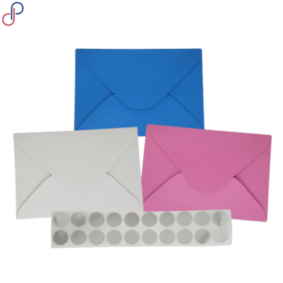 Tres sobres fototarjeta de colores (azul, blanco y rosa) y una tira de pegatinas adhesivas circulares para sellarlos.